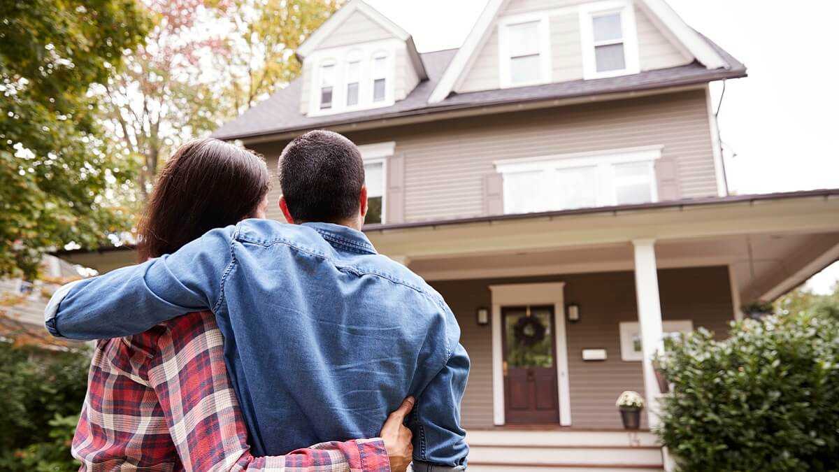 A couple standing admiring the outside of a house.