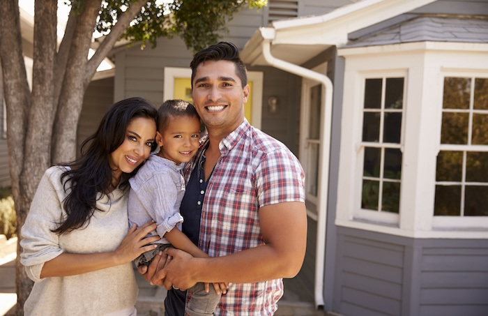 Hispanic family standing outside of home.