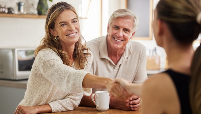 Couple shaking hands to make a deal with an agent.