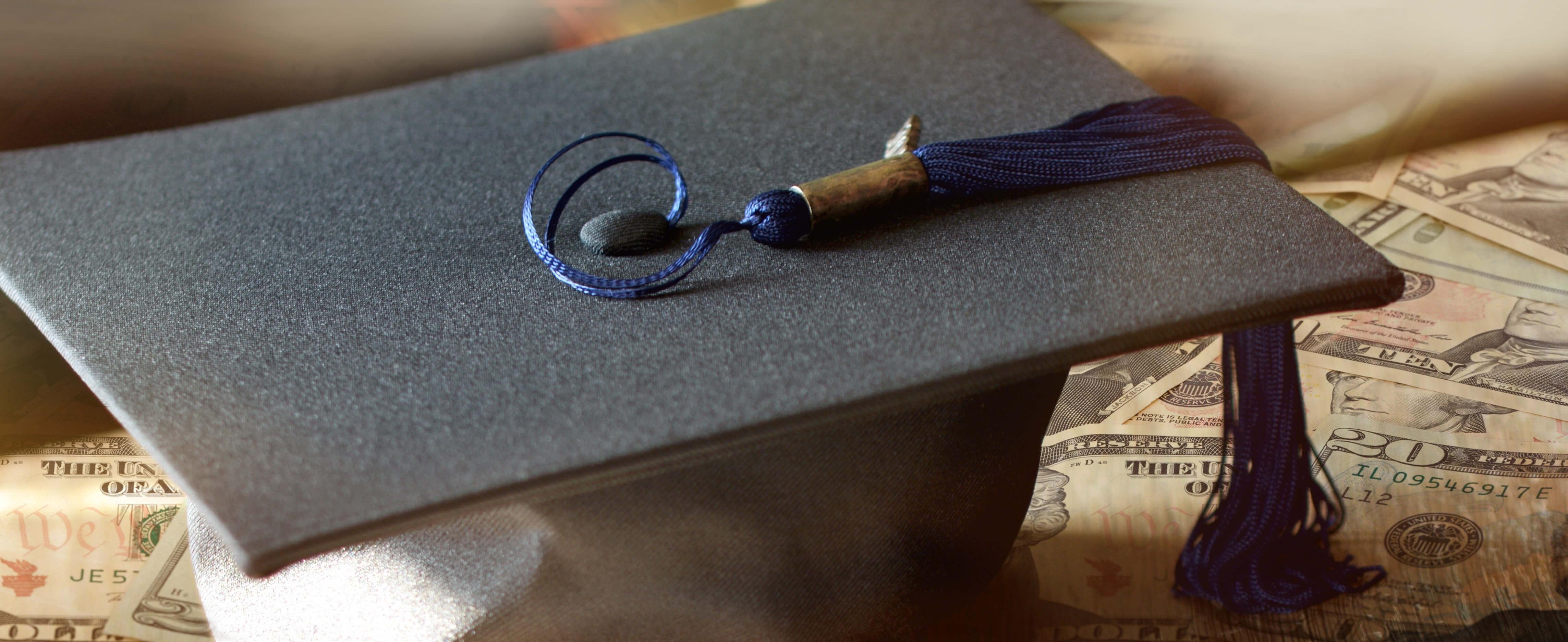 Student mortar board on a pile of cash.