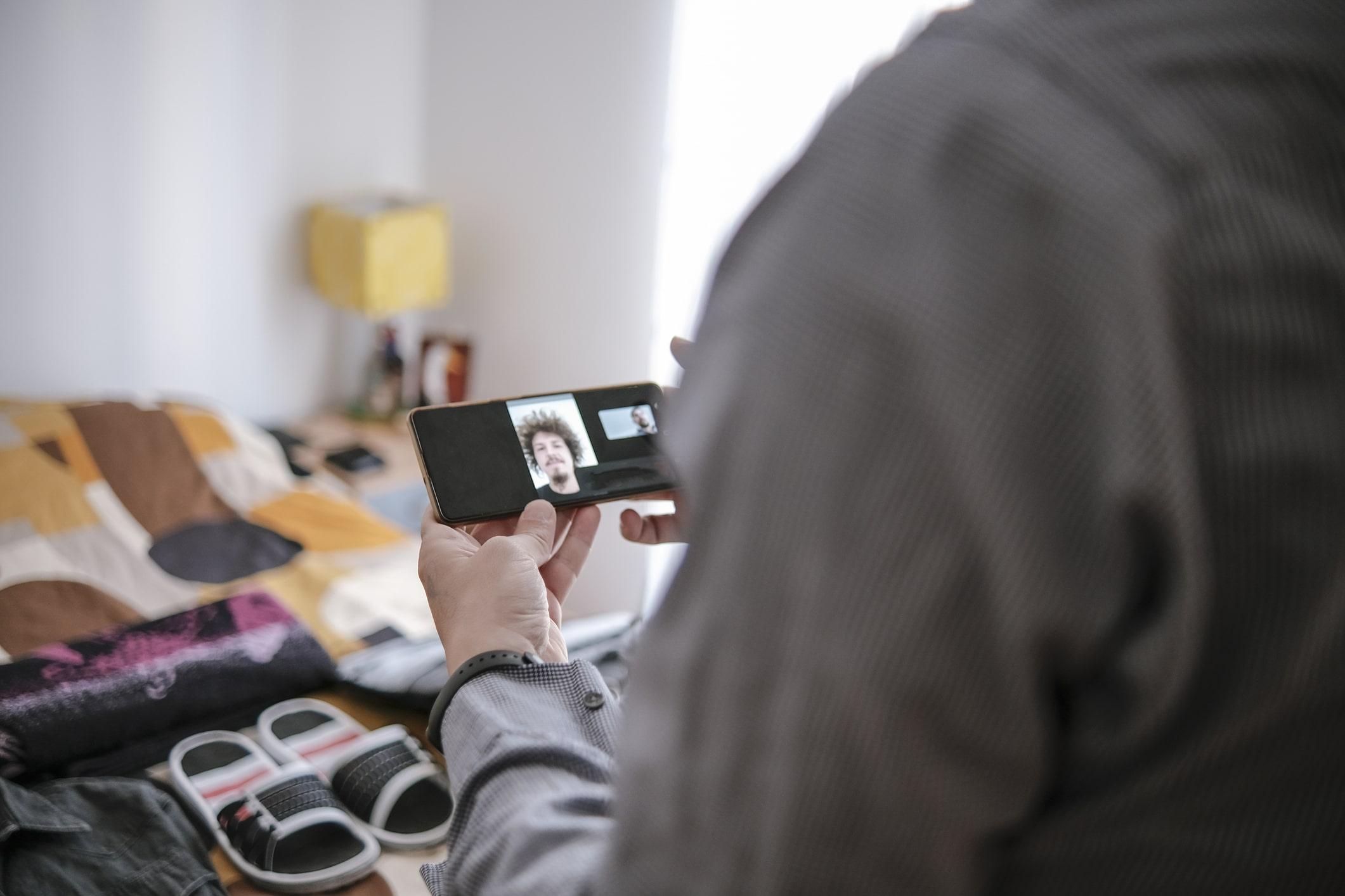Overseas servicemember video chatting with loan officer. A packed, open suitcase can be seen in the background